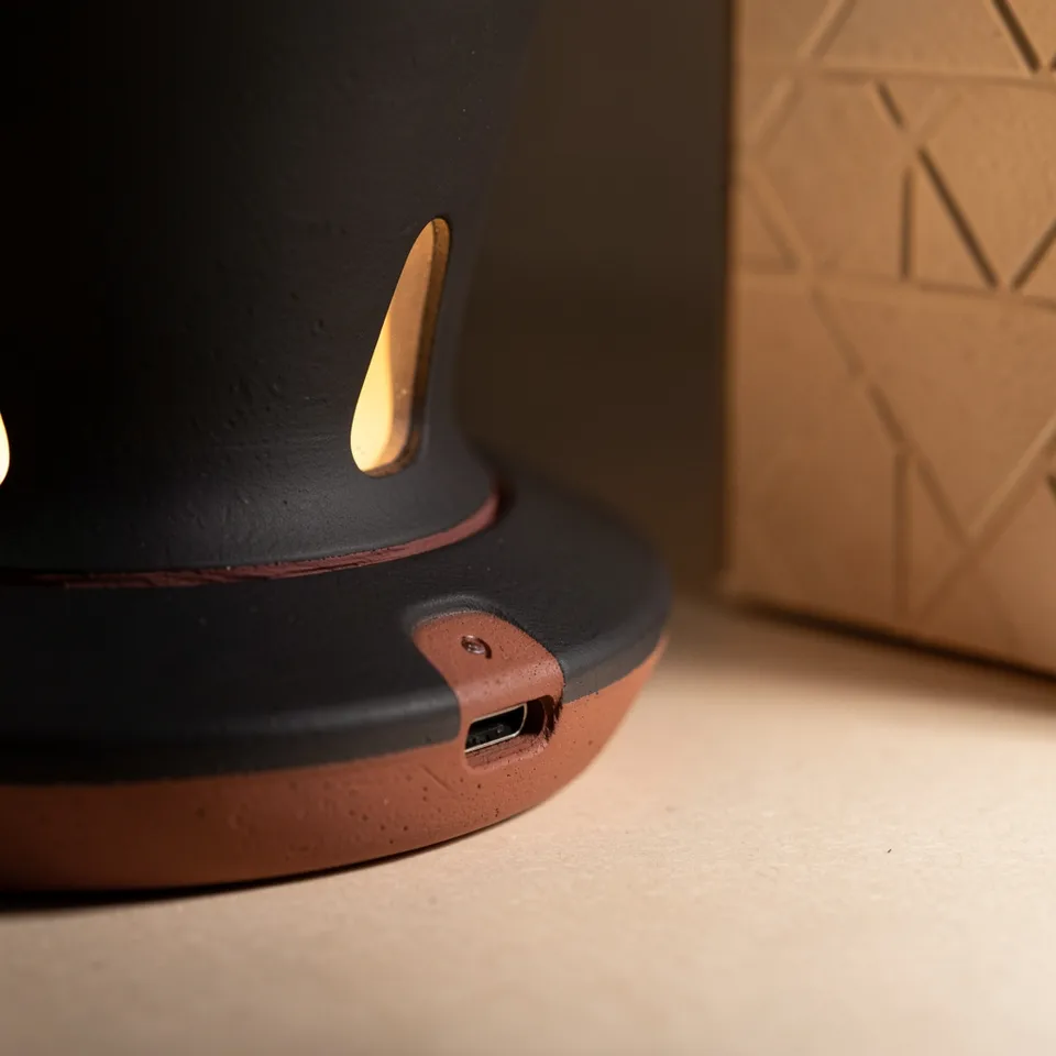 Macro detail of the dripper's stoneware base, terracotta seam and USB-C charging port